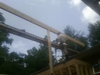 Carpenter setting a ridge beam over a new addition frame — Ice Dam Removal by Roofing Brothers in Manley