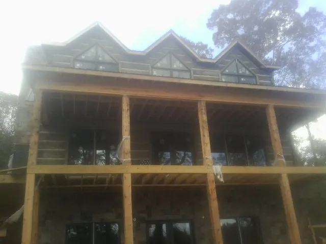 Dormers and porch framing on a large log home under construction — Roof Coating work by our crew in Manley