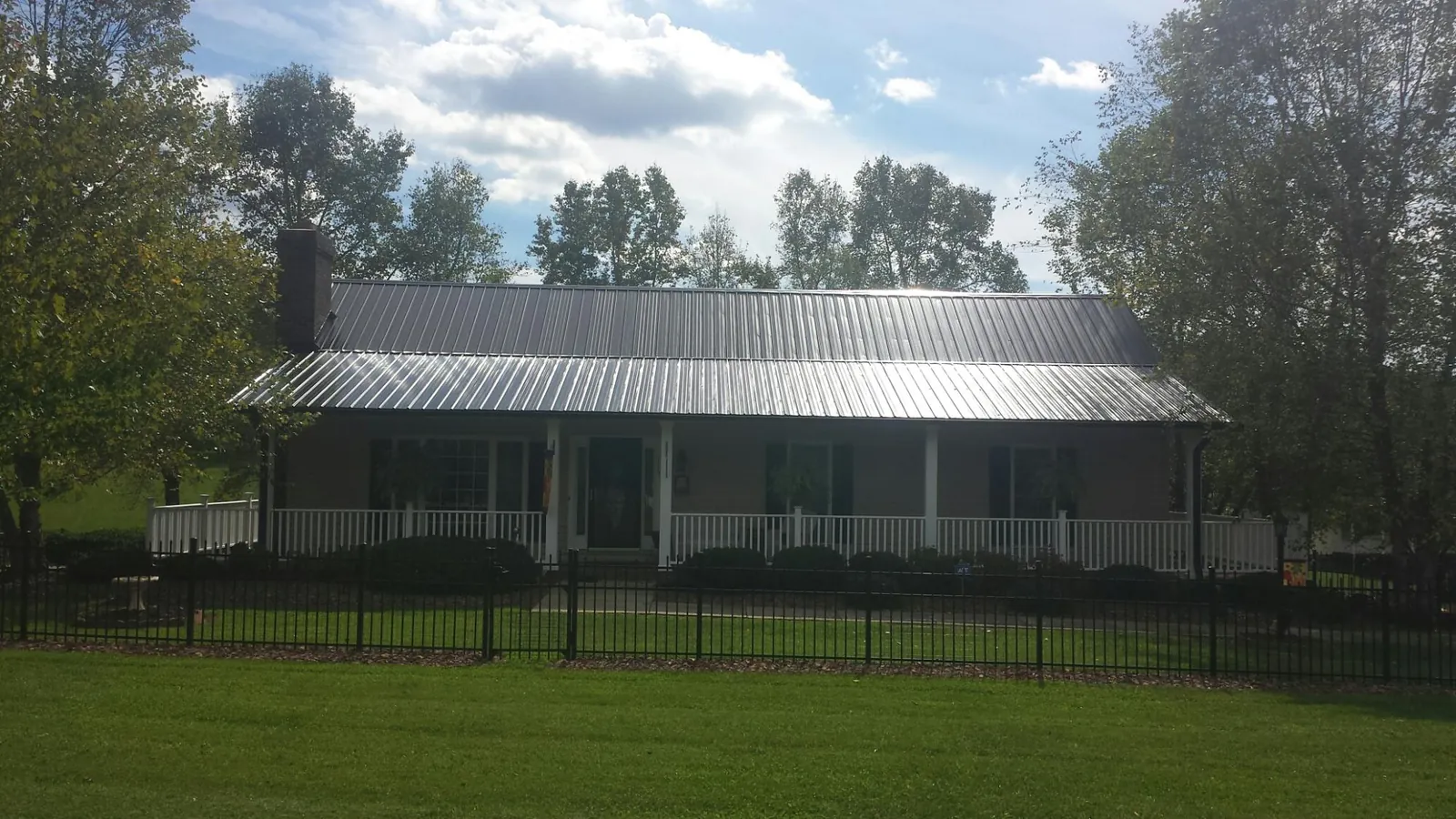 Gray metal roof on a brick ranch with a full width front porch — Gutter Guard Installation work by our crew in Manley