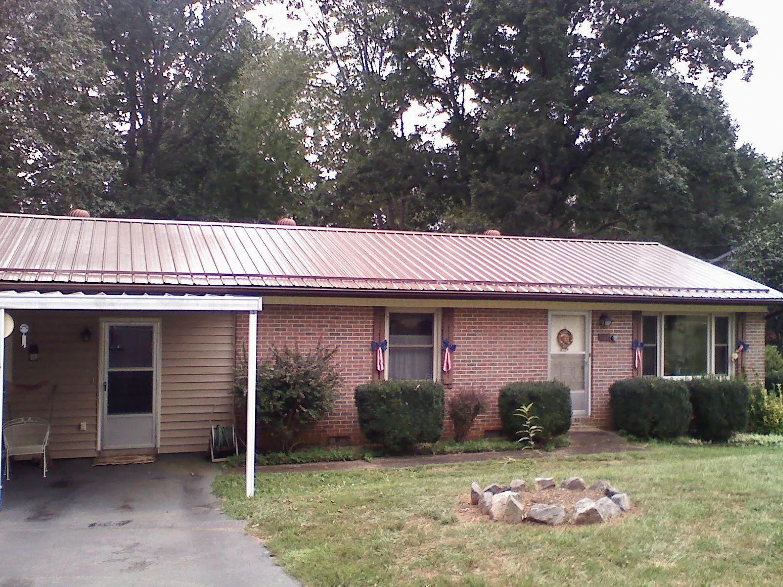Bronze metal roof and carport on a brick ranch home — Roof Repair work by our crew in Manley