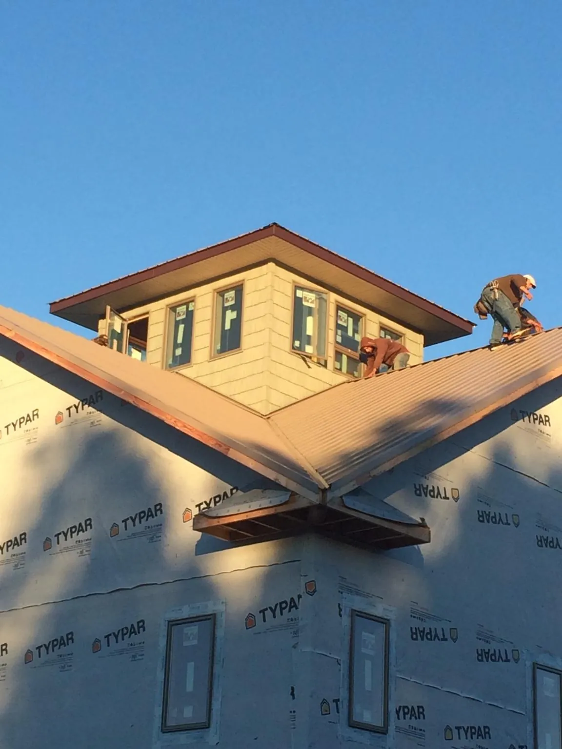 Roofers working around a rooftop cupola on a new metal roof at sunset — Roof Waterproofing in Manley by Roofing Brothers